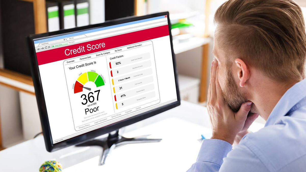Man looking at his poor credit score displayed on his computer's screen, wondering how he could ever get a car loan with such bad credit. He's also interested in improving his credit score.