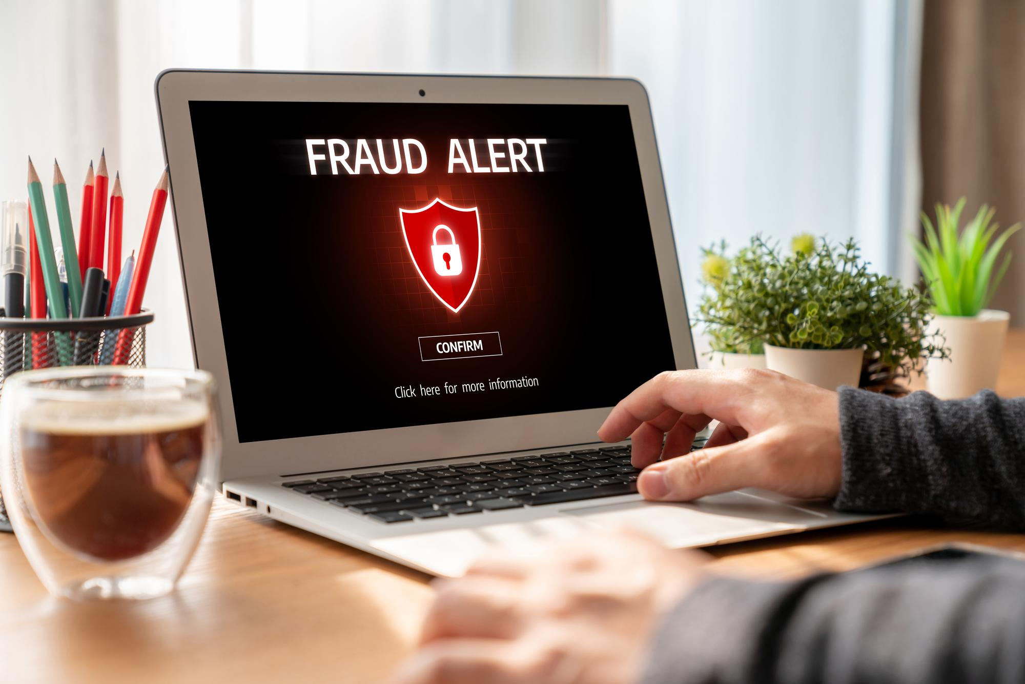 A laptop screen displaying FRAUD ALERT!