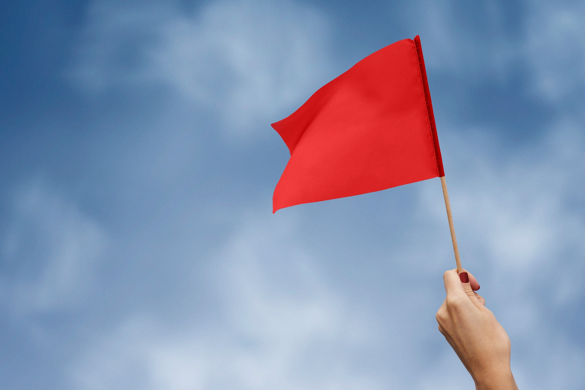 A hand holding a red flag.